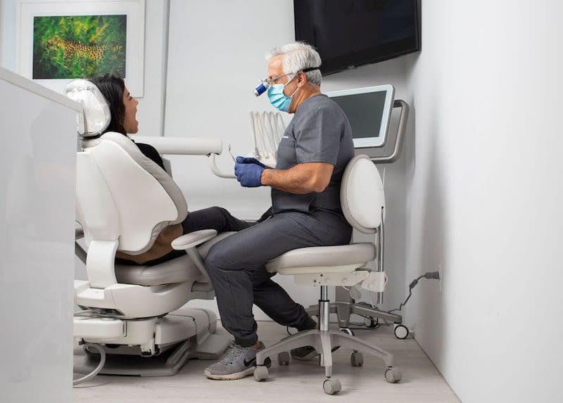 dentist sitting in chair with patient mouth open rejuvenation health