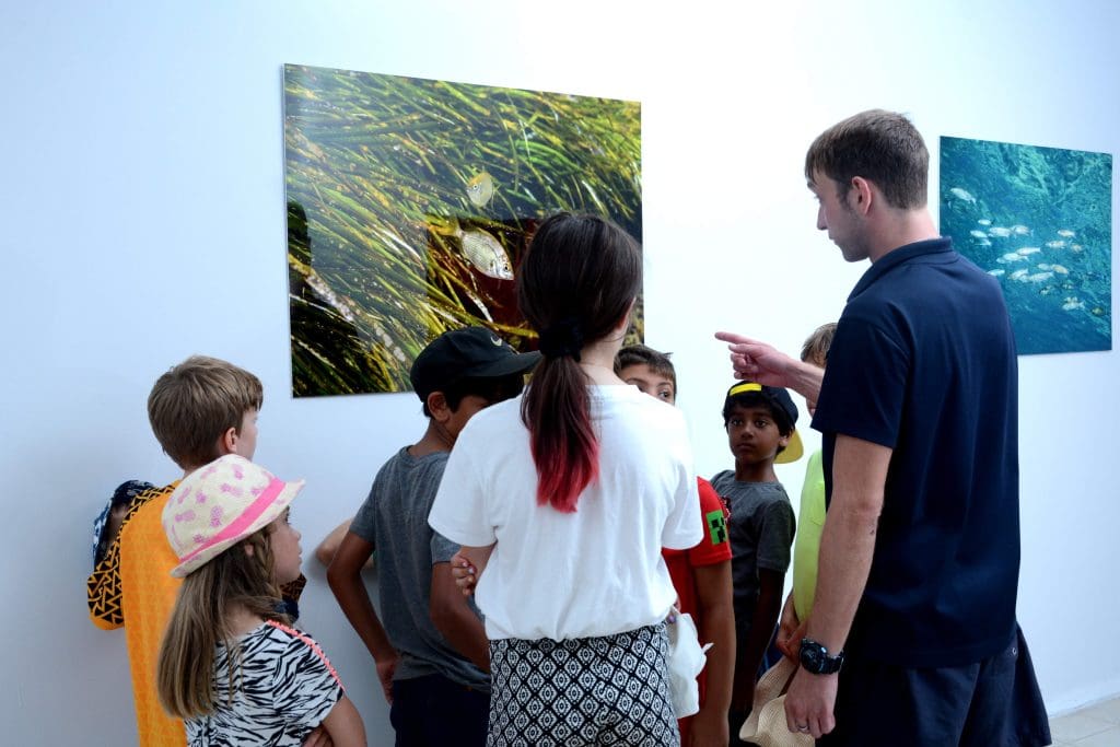 children and teacher looking at photos of fish marine life