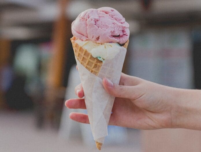 person holding strawberry ice cream cone outside - East End Taste Magazine
