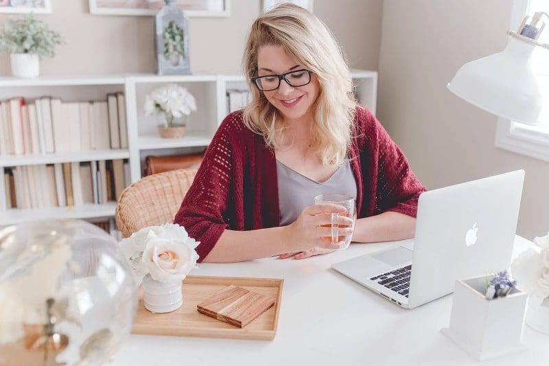 woman with blonde hair and glasses red sweater sitting at desk