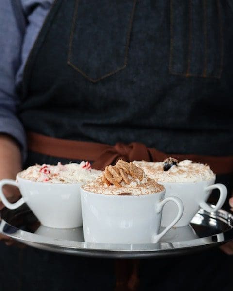 man holding cocktails denim apron festive holiday drinks hot chocolate