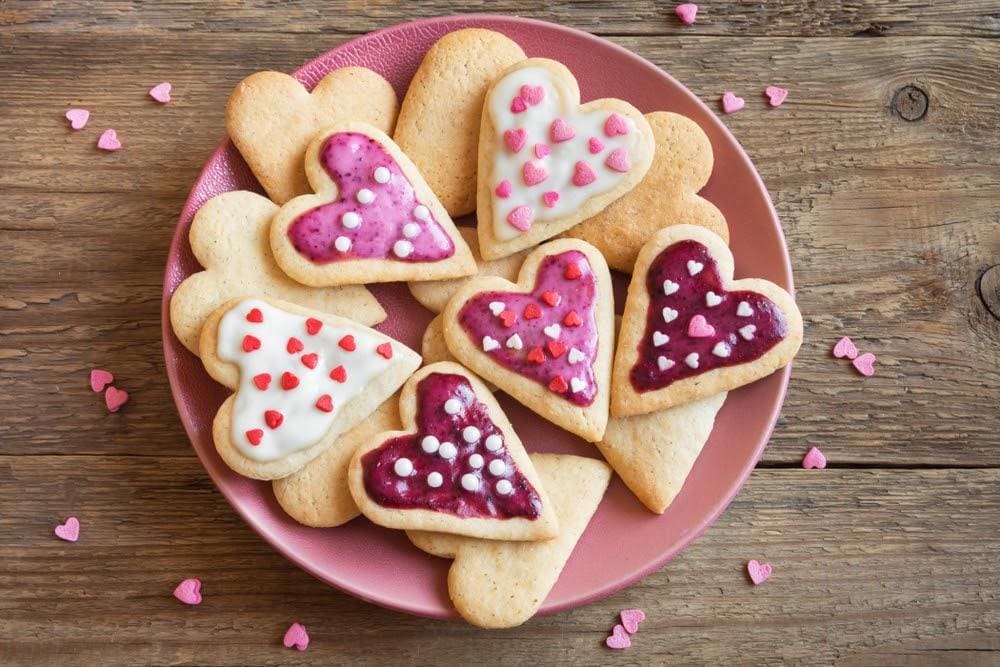 plate of valentine's sugar cookies with pink and white icing sprinkles