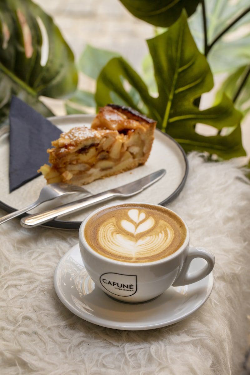 cake slice and cappuccino with latte art painted leaf background
