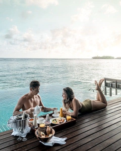 couple at water deck eating breakfast tropical paradise brown hair man woman