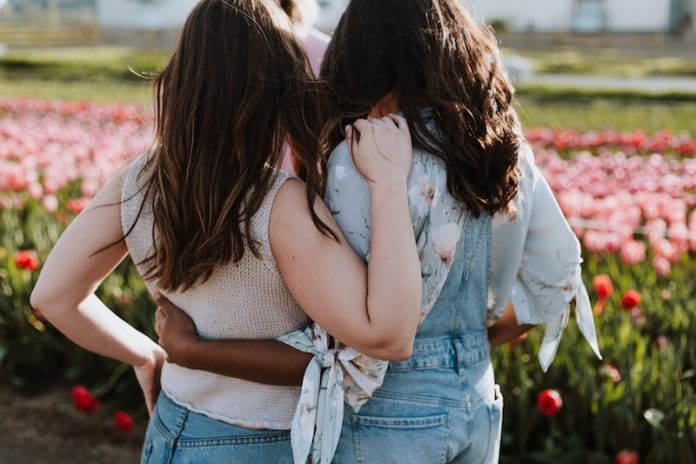 two women hugging near flower field pink - East End Taste Magazine
