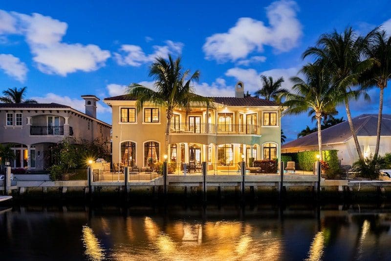 luxury home by the water at night palm trees clear sky