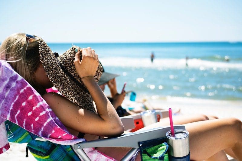 woman at beach with drink beach chair blue sky