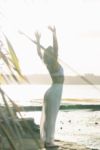 woman doing yoga by the bay wearing all white