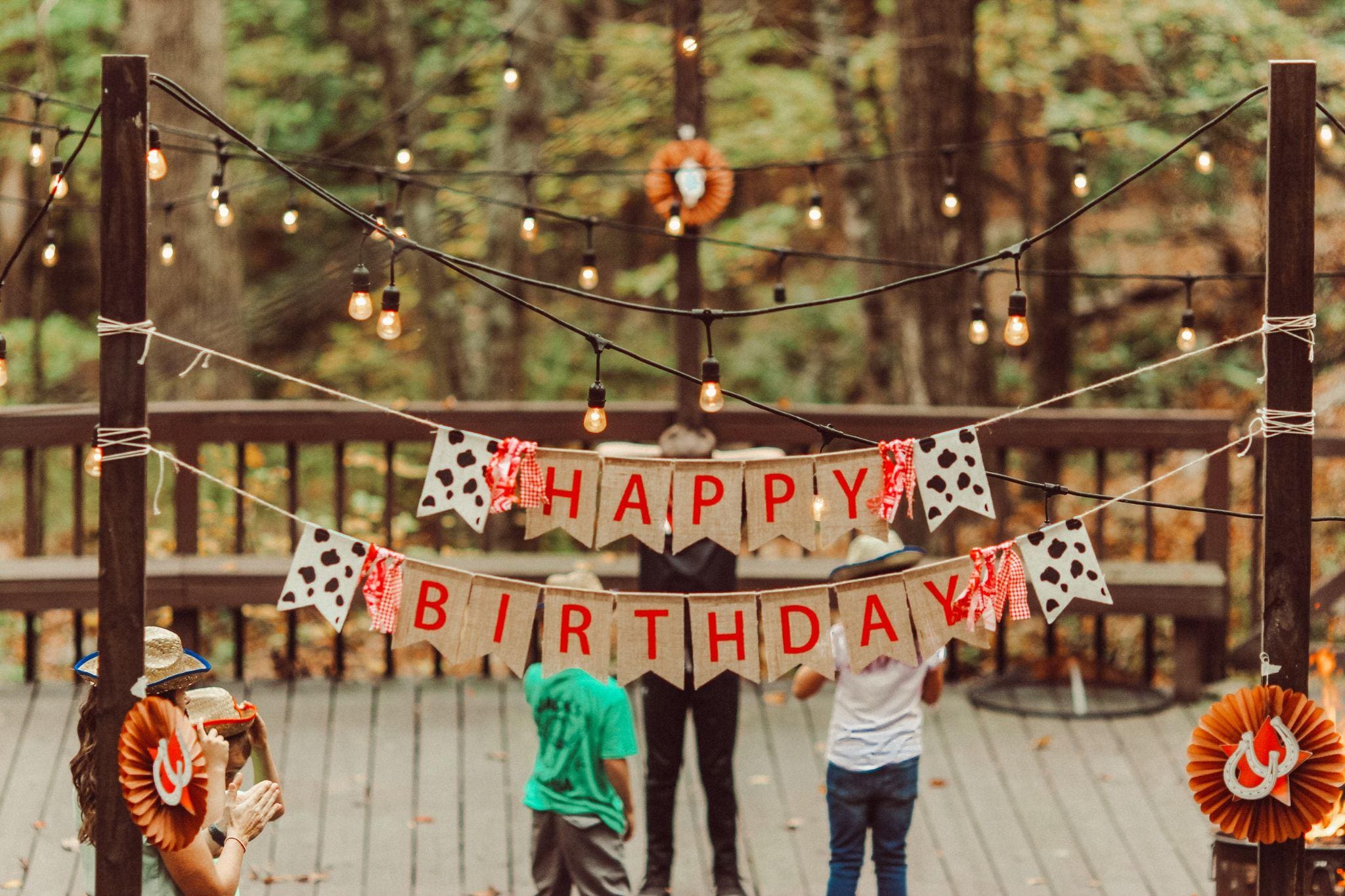 happy birthday outdoor banner sign on wooden deck string lights
