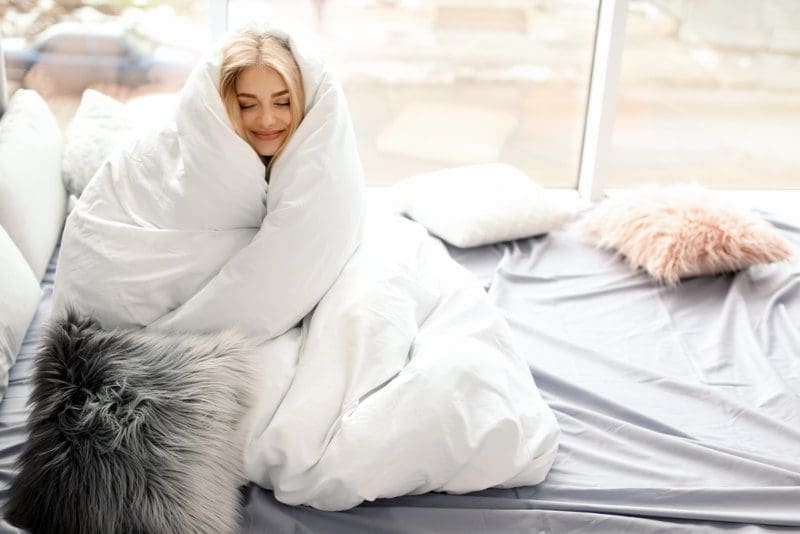 woman wrapped in warm comforter blanket with blonde hair