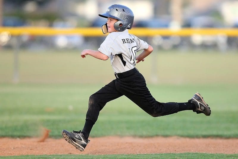 young boy playing baseball running fast
