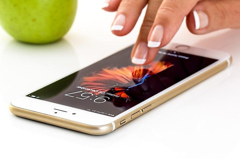 woman's manicured hands using smart phone