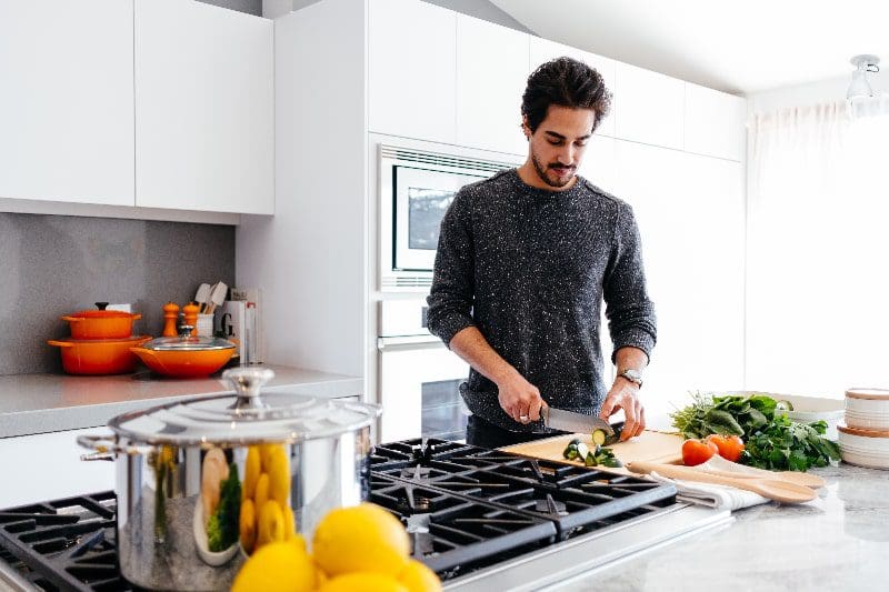 man in kitchen cooking a healthy meal