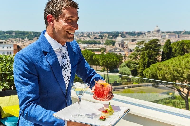 terrace restaurant manager serving cocktails rome city backdrop