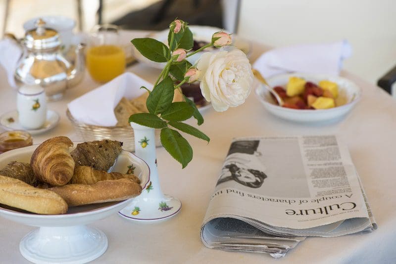 breakfast table with white tablecloth and newspaper