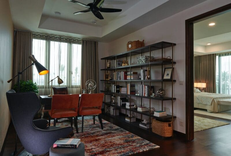 home office setup with bookshelf and fan rug