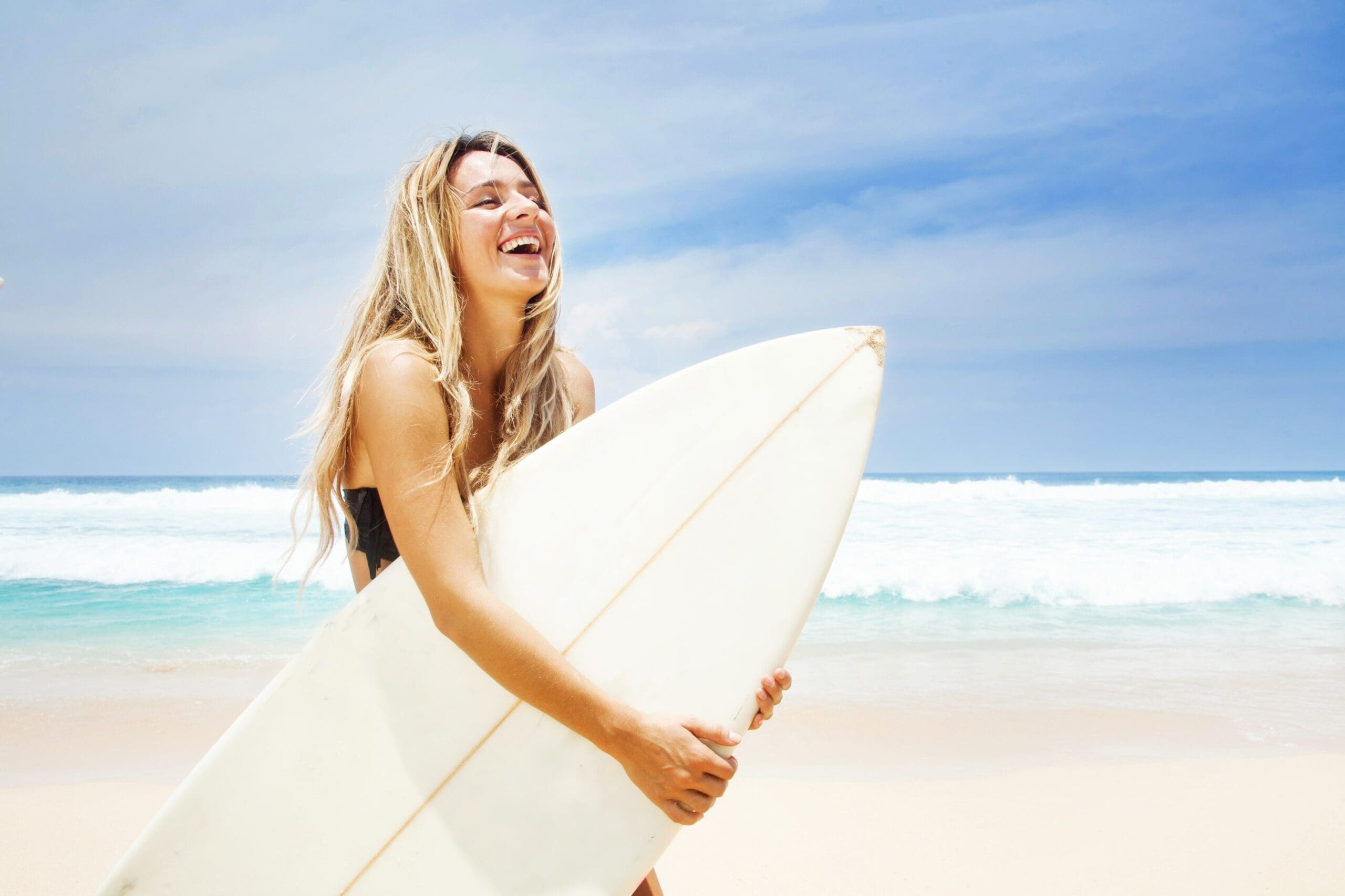 young woman blonde hair girl holding surfboard