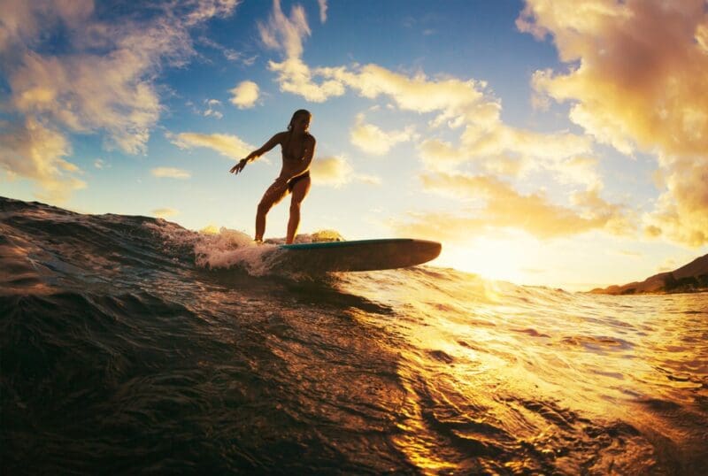 woman surfing in the sunrise hawaii