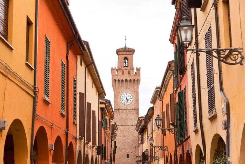 Street with houses and tower with clock in Castel San Pietro