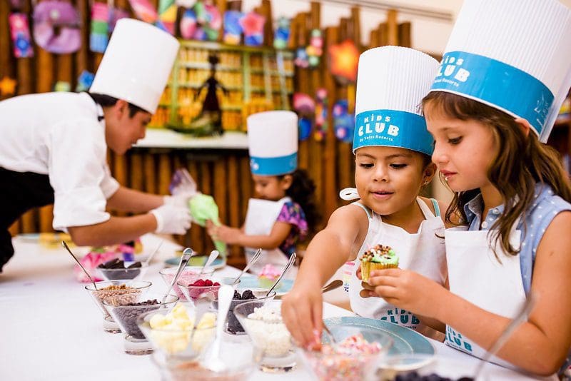 children with chefs' hats making cupcakes