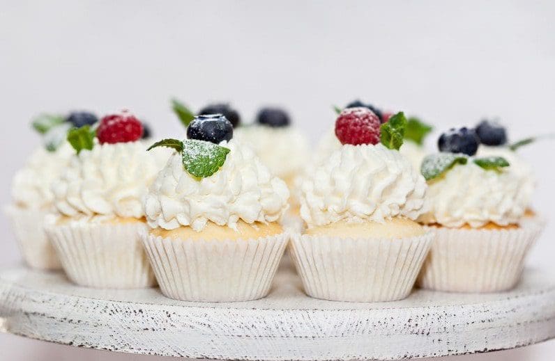delicious pretty white cupcakes with fruit and garnish