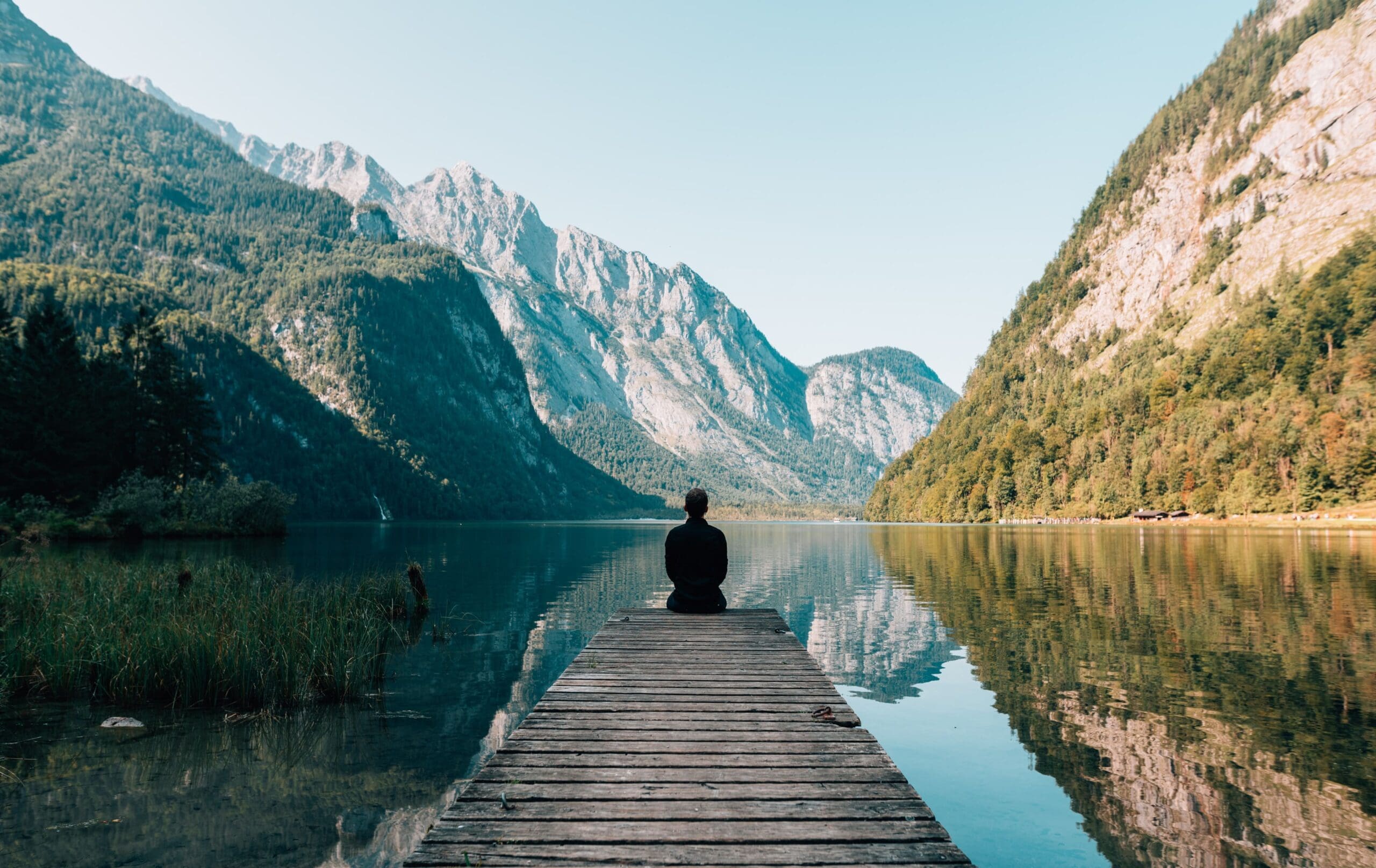 luxury rehab person meditating wellness retreat in mountains lake