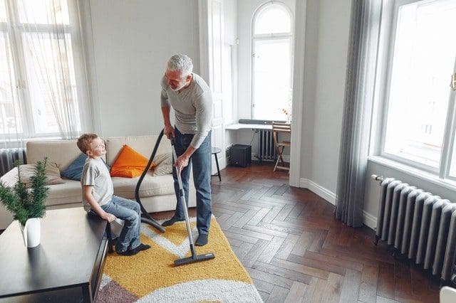 man cleaning the carpet with grandson natural light