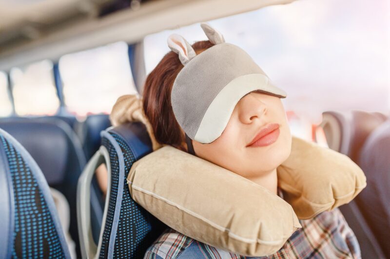 woman sleeping with eye mask on airplane travel pillow
