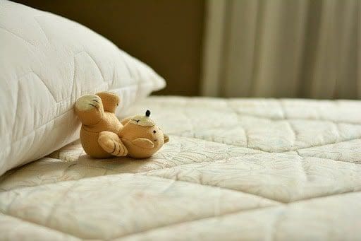 teddy bear on white cream bed