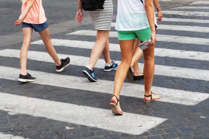 summery clothed people crossing the street at crosswalk