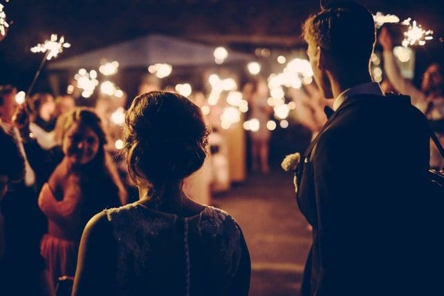 man woman couple standing outside sparklers wedding line