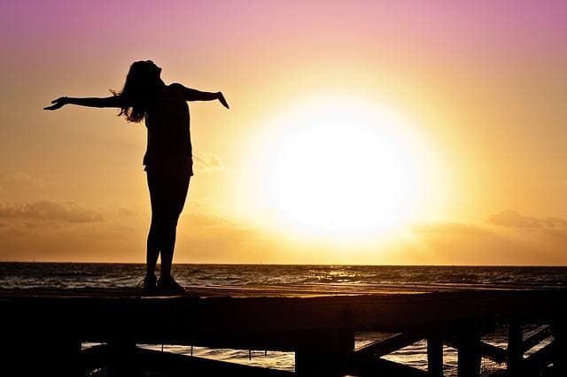 woman outstretched arms looking at sun