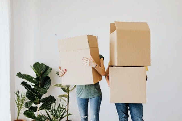 couple wearing jeans covering faces with moving boxes