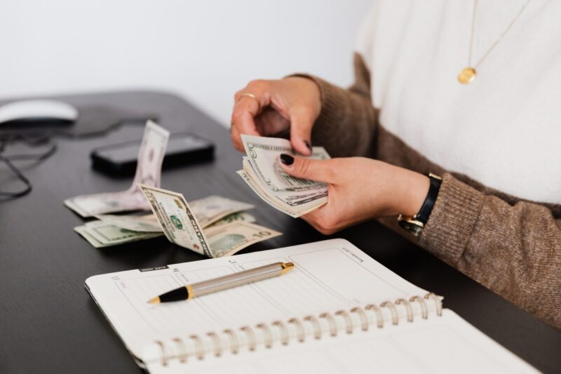 person counting money at their work desk