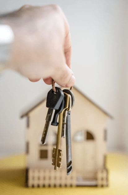 person holding keys in front of model home