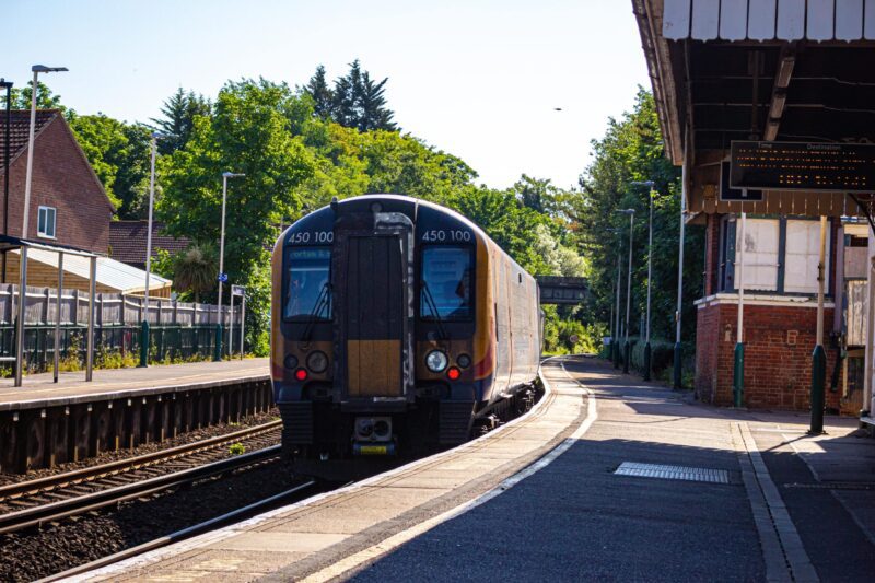 train leaving train station green leaves on trees