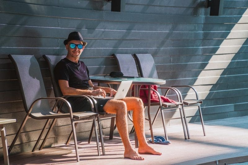 man working at computer by the pool