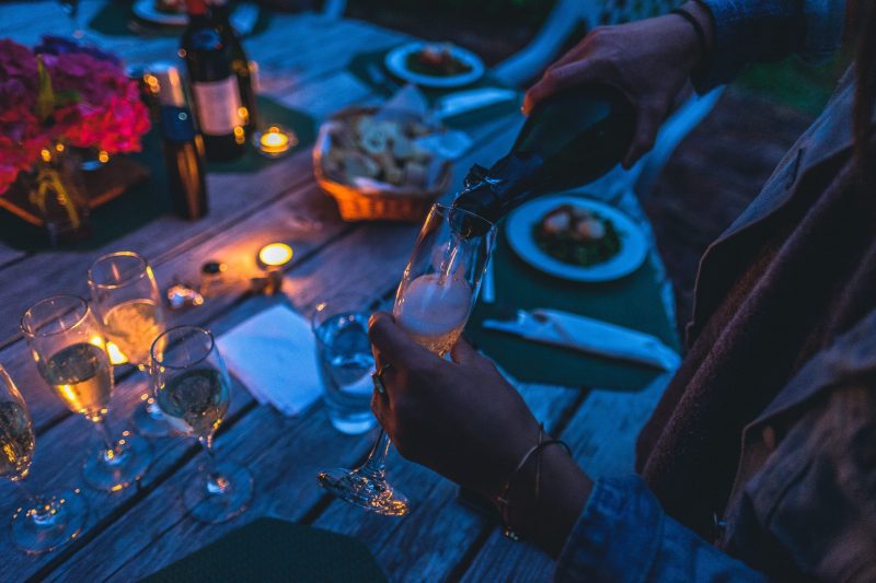 person pouring glass of champagne outside evening