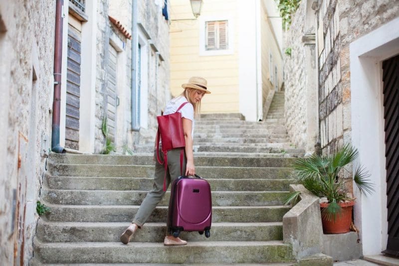 Woman walking up stone steps travel with luggage