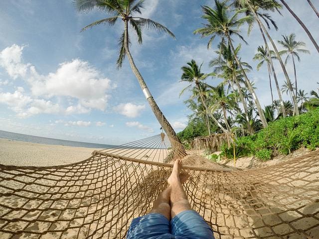 man relaxing on hammock at the beach