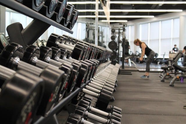 woman standing surrounded by exercise equipment at gym