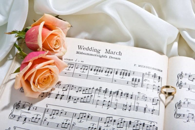 wedding sheet music on bed with roses