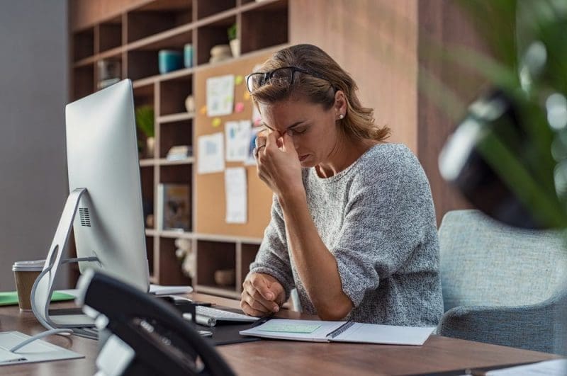 Exhausted businesswoman having a headache in modern office