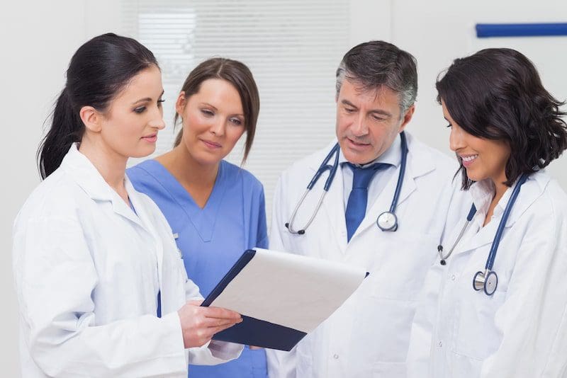Nurse and doctors looking at clipboard