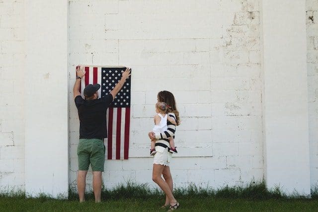man hanging USA flag on white wall