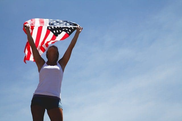 woman white shirt holding USA flag