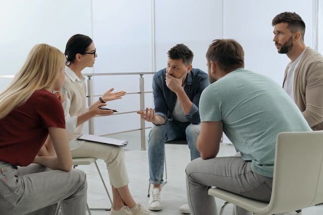 Psychotherapist working with group of drug addicted people therapy session