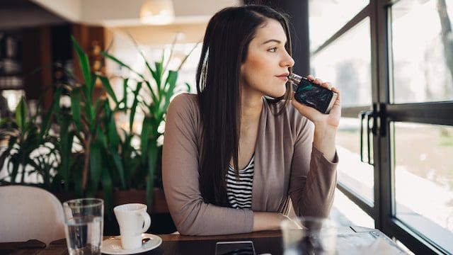 Young woman using electronic cigarette to smoke in public places