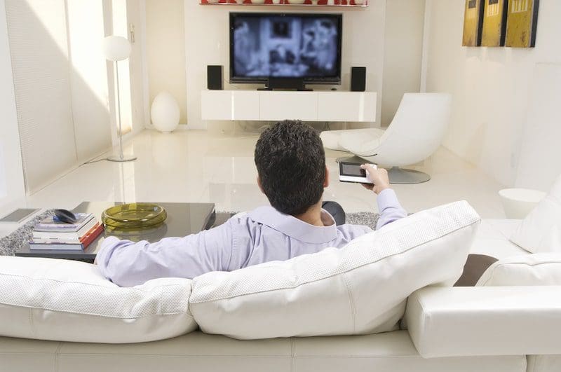 man watching TV white couch living room