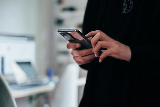 man wearing black shirt scrolling on smart phone